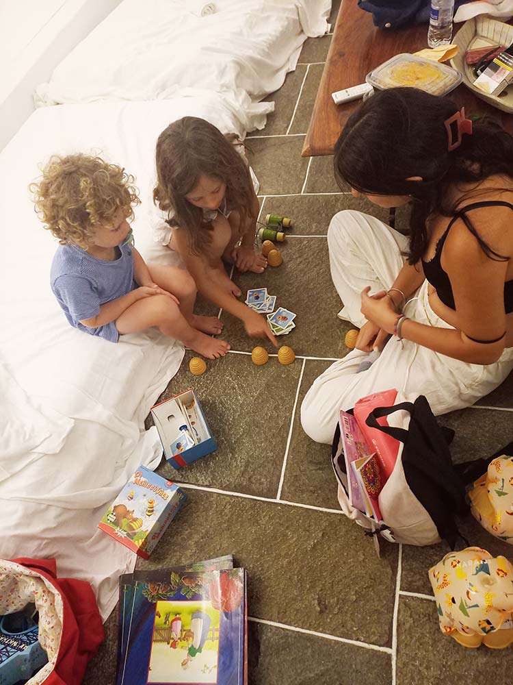 Babysitter playing educational games with two young children during indoor babysitting